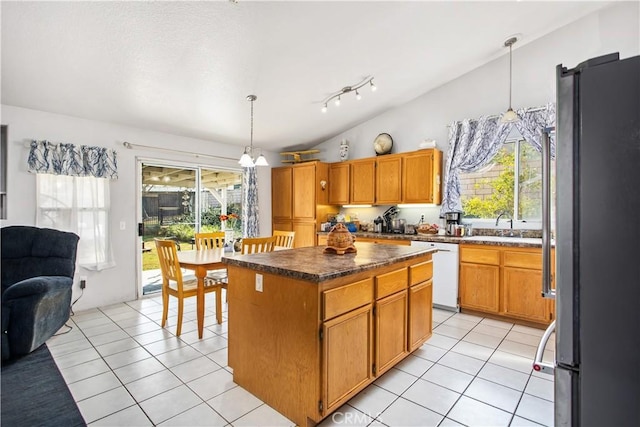 kitchen with a center island, hanging light fixtures, light tile patterned floors, stainless steel refrigerator, and white dishwasher