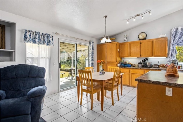 tiled dining room featuring vaulted ceiling and a textured ceiling