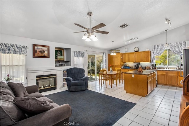 tiled living room with sink, ceiling fan, a fireplace, a textured ceiling, and vaulted ceiling