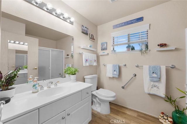 bathroom with vanity, toilet, a shower with shower door, and wood-type flooring