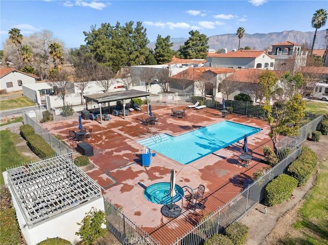 view of pool featuring a hot tub, a mountain view, and a patio