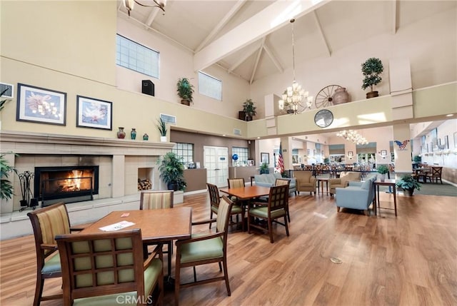 dining room with hardwood / wood-style flooring, a chandelier, lofted ceiling with beams, and a tile fireplace