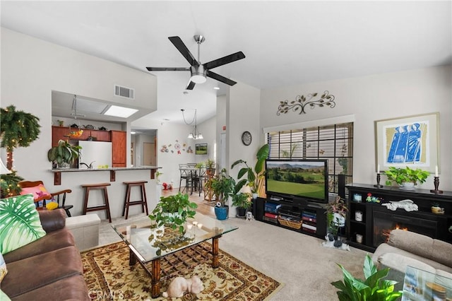 living room featuring light carpet, ceiling fan with notable chandelier, and lofted ceiling