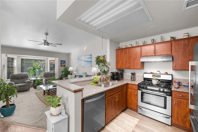 kitchen featuring light stone counters, sink, kitchen peninsula, and appliances with stainless steel finishes