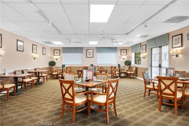 carpeted dining space featuring rail lighting, a paneled ceiling, and ceiling fan