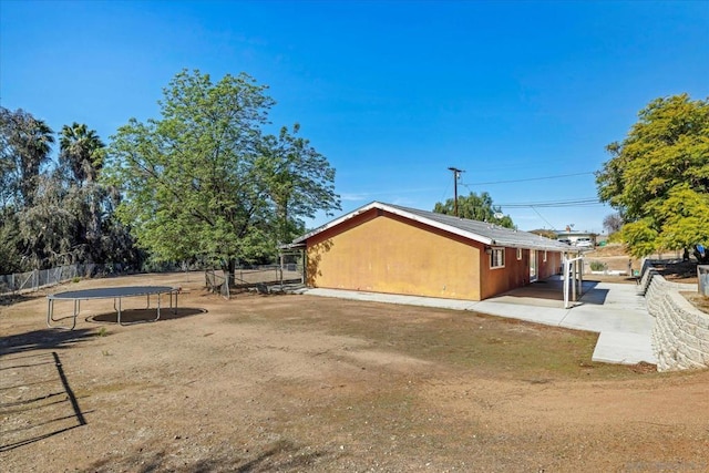 view of side of home featuring a patio area and a trampoline