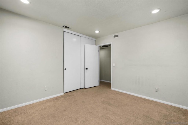 unfurnished bedroom featuring light colored carpet and a closet