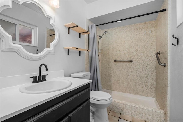 bathroom with tile patterned flooring, vanity, a tile shower, and toilet