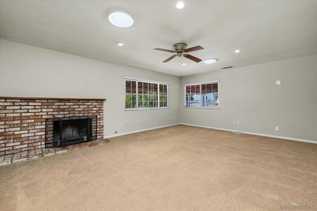 unfurnished living room featuring ceiling fan, light colored carpet, and a brick fireplace