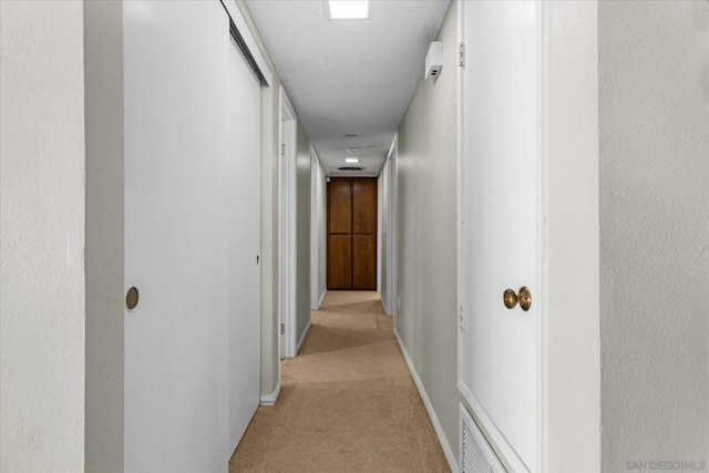 corridor featuring light carpet and a textured ceiling