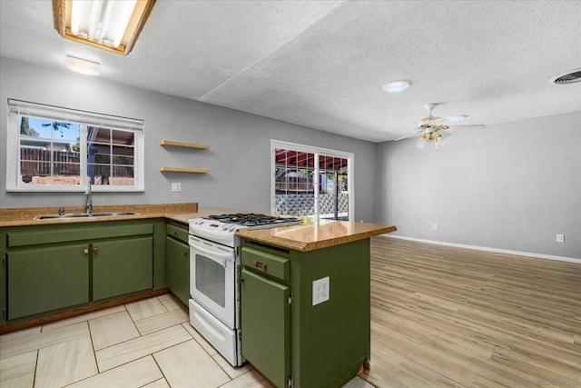 kitchen with sink, white range with gas cooktop, green cabinets, kitchen peninsula, and a textured ceiling