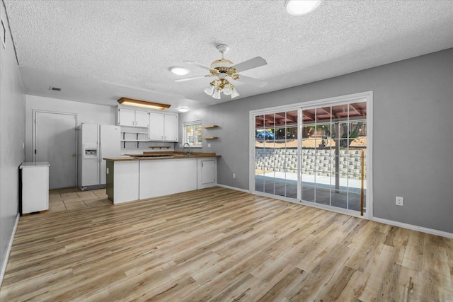 kitchen featuring white cabinetry, sink, white fridge with ice dispenser, light hardwood / wood-style floors, and kitchen peninsula