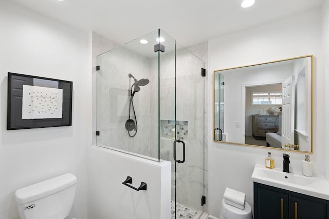 bathroom featuring a shower with door, vanity, and toilet