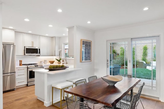 dining space featuring ornamental molding and light hardwood / wood-style floors