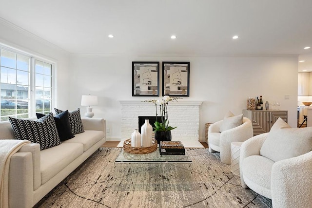 living room featuring hardwood / wood-style flooring, crown molding, and a brick fireplace