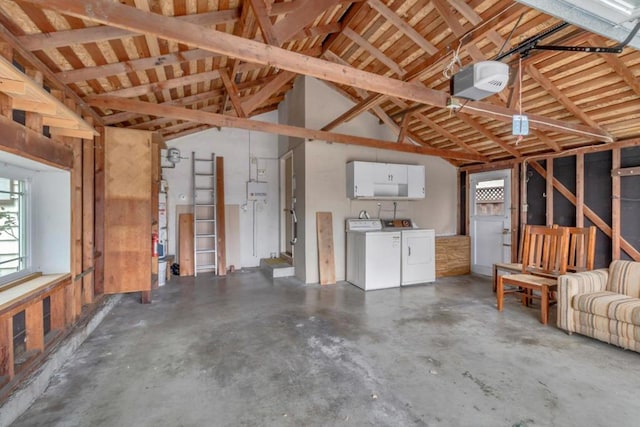 garage with washing machine and clothes dryer, a garage door opener, and water heater