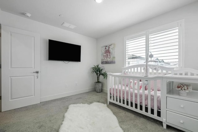 carpeted bedroom featuring a nursery area