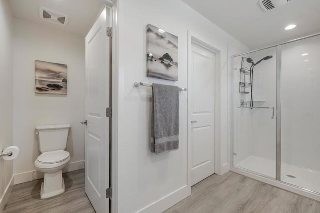 bathroom with hardwood / wood-style floors, a shower with door, and toilet