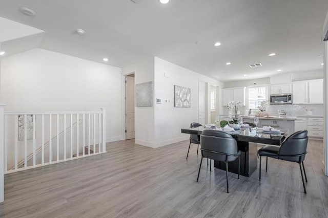 dining room featuring lofted ceiling and light hardwood / wood-style flooring