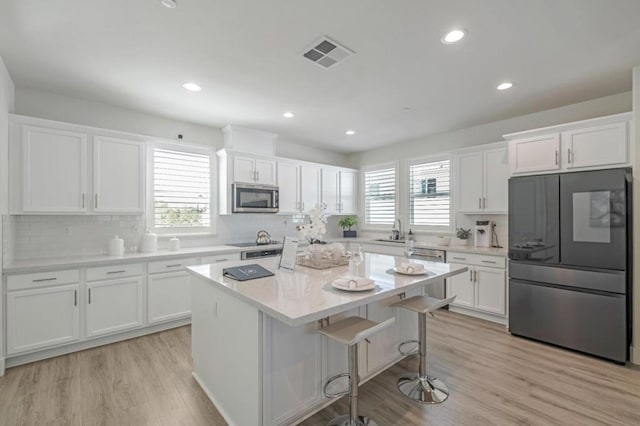 kitchen featuring white cabinetry, a breakfast bar area, stainless steel appliances, and a kitchen island