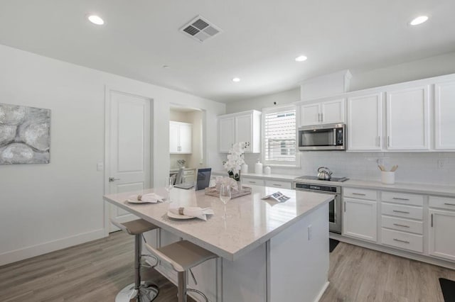 kitchen with white cabinetry, appliances with stainless steel finishes, a center island, and a kitchen breakfast bar