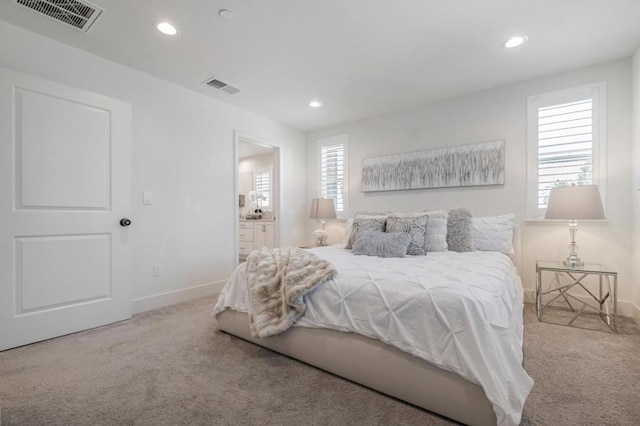 bedroom with ensuite bathroom and light colored carpet