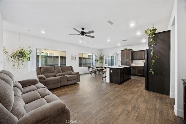 living room featuring ceiling fan, sink, and dark hardwood / wood-style flooring