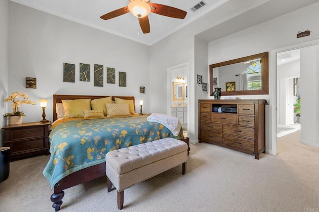 bedroom with ensuite bathroom, light carpet, and ceiling fan