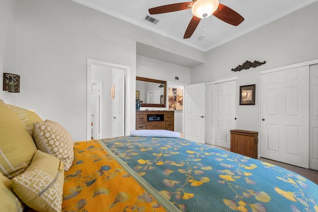 bedroom featuring ensuite bathroom, crown molding, two closets, ceiling fan, and carpet