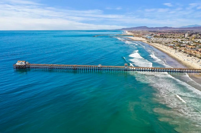 drone / aerial view with a water and mountain view and a beach view