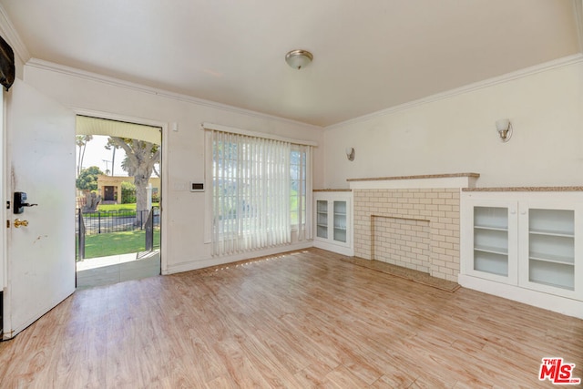 unfurnished living room featuring a brick fireplace, crown molding, and light hardwood / wood-style floors