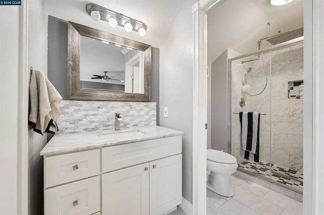 bathroom with backsplash, vanity, ceiling fan, toilet, and a shower with door