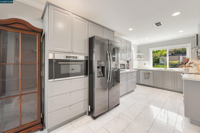 kitchen featuring sink, tasteful backsplash, ornamental molding, appliances with stainless steel finishes, and gray cabinets