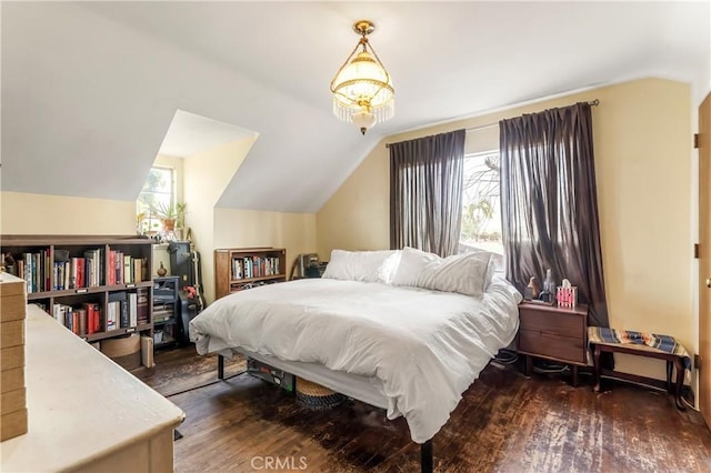 bedroom featuring dark wood-type flooring, vaulted ceiling, and multiple windows