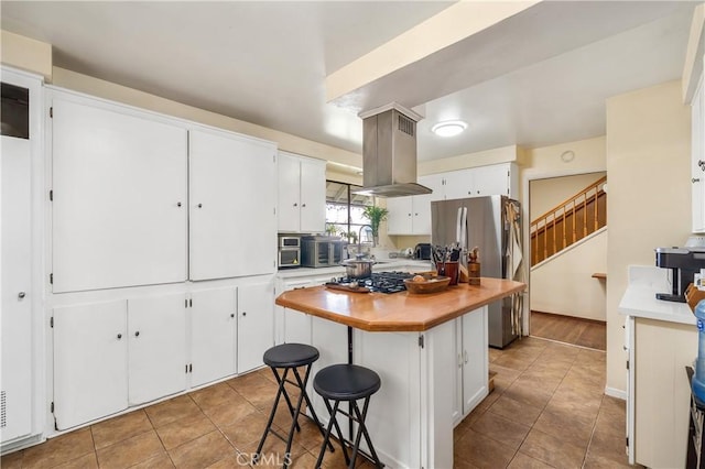 kitchen featuring a breakfast bar area, white cabinets, island exhaust hood, a center island, and light tile patterned floors