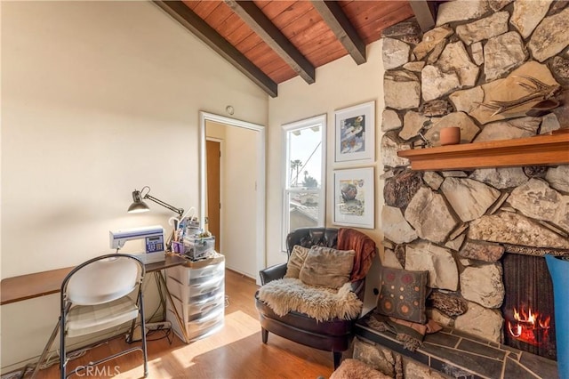 living area featuring lofted ceiling with beams, hardwood / wood-style floors, wooden ceiling, and a fireplace