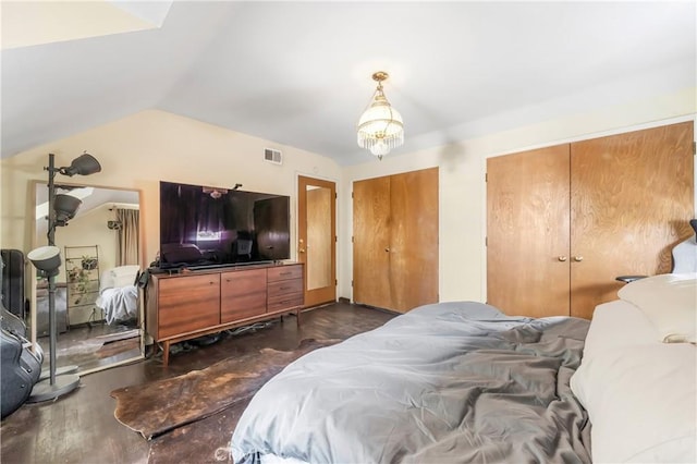 bedroom with multiple closets, lofted ceiling, and a notable chandelier