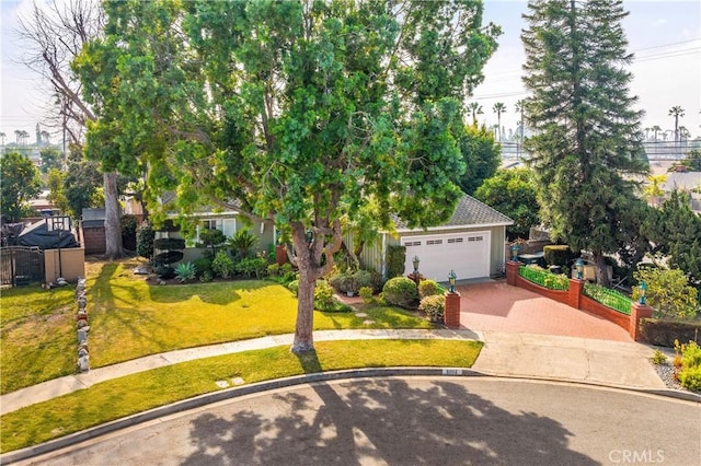 view of property hidden behind natural elements with a garage and a front yard