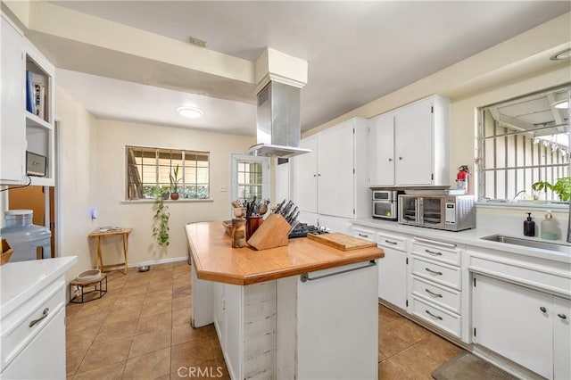 kitchen featuring light tile patterned floors, a center island, white cabinets, and island exhaust hood