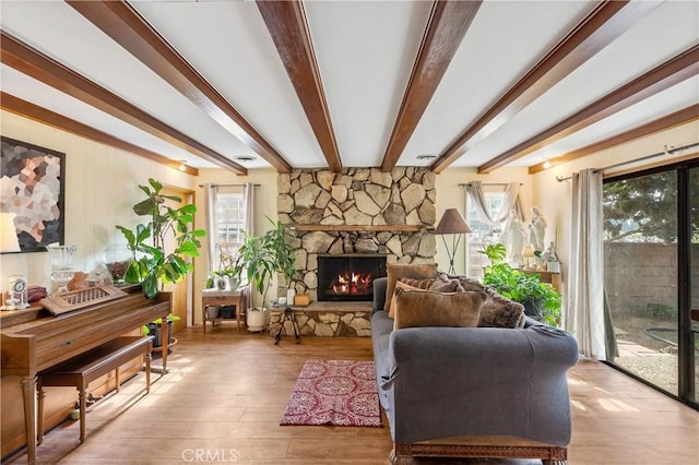 sitting room featuring beam ceiling, a stone fireplace, and hardwood / wood-style flooring