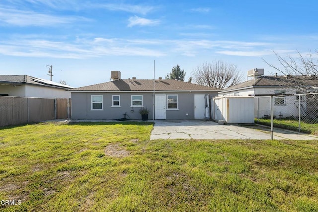 rear view of property with a yard, a storage unit, and a patio area