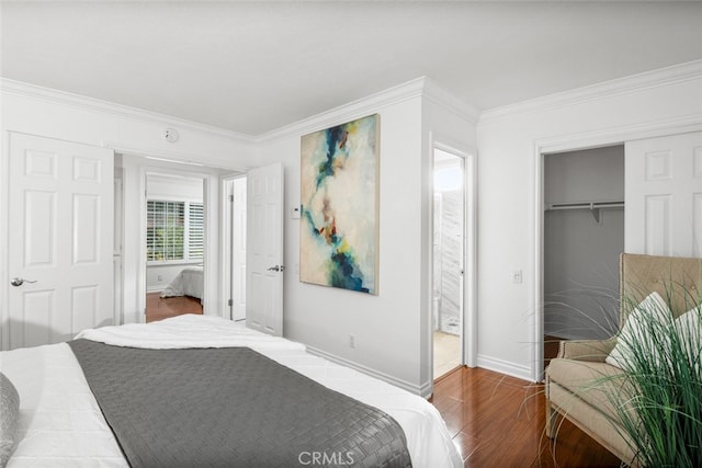 bedroom with hardwood / wood-style floors, crown molding, ensuite bath, and a closet