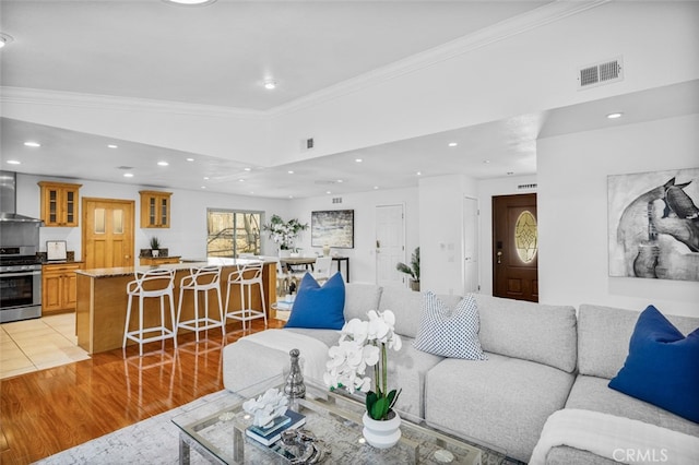 living room featuring crown molding, vaulted ceiling, and light hardwood / wood-style flooring