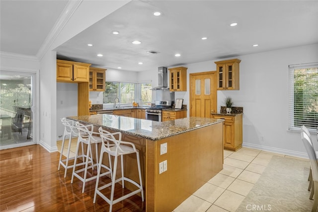 kitchen featuring plenty of natural light, a center island, stone countertops, gas range, and wall chimney exhaust hood