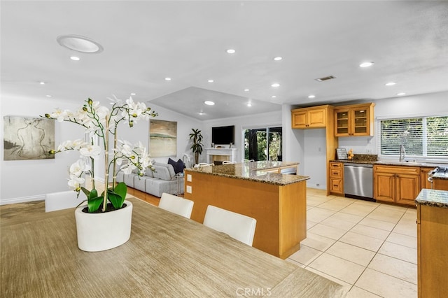 kitchen with light tile patterned flooring, stone countertops, sink, a breakfast bar area, and stainless steel dishwasher