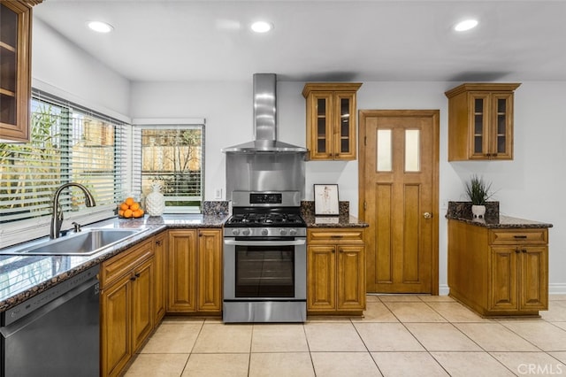 kitchen featuring black dishwasher, dark stone countertops, sink, wall chimney range hood, and stainless steel range with gas stovetop