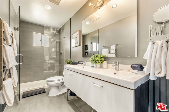 bathroom featuring vanity, a shower with door, and toilet