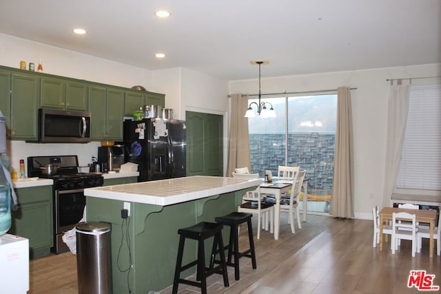 kitchen with green cabinetry, appliances with stainless steel finishes, tile counters, and light wood-type flooring