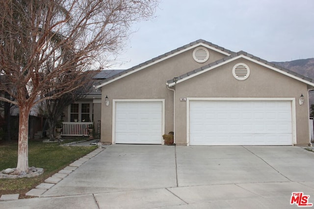 ranch-style house with a garage and solar panels