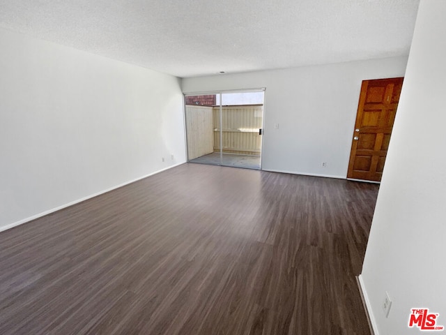 spare room featuring dark hardwood / wood-style floors and a textured ceiling